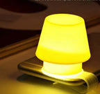 Cute silicone mobile phone holder night light on a bedside table