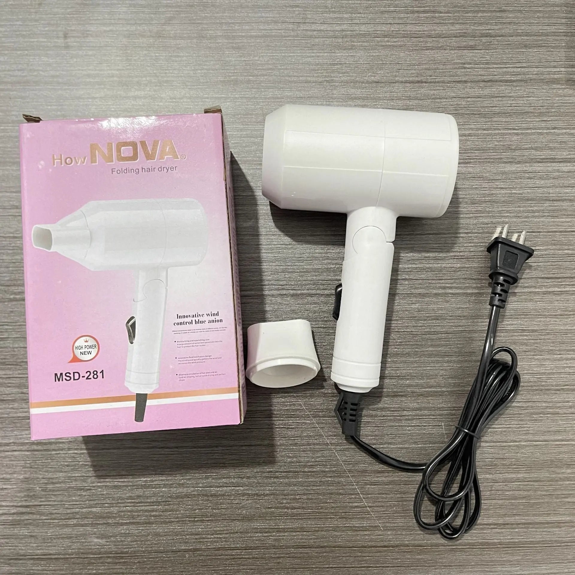 White hair dryer with packaging and plug on a wooden surface