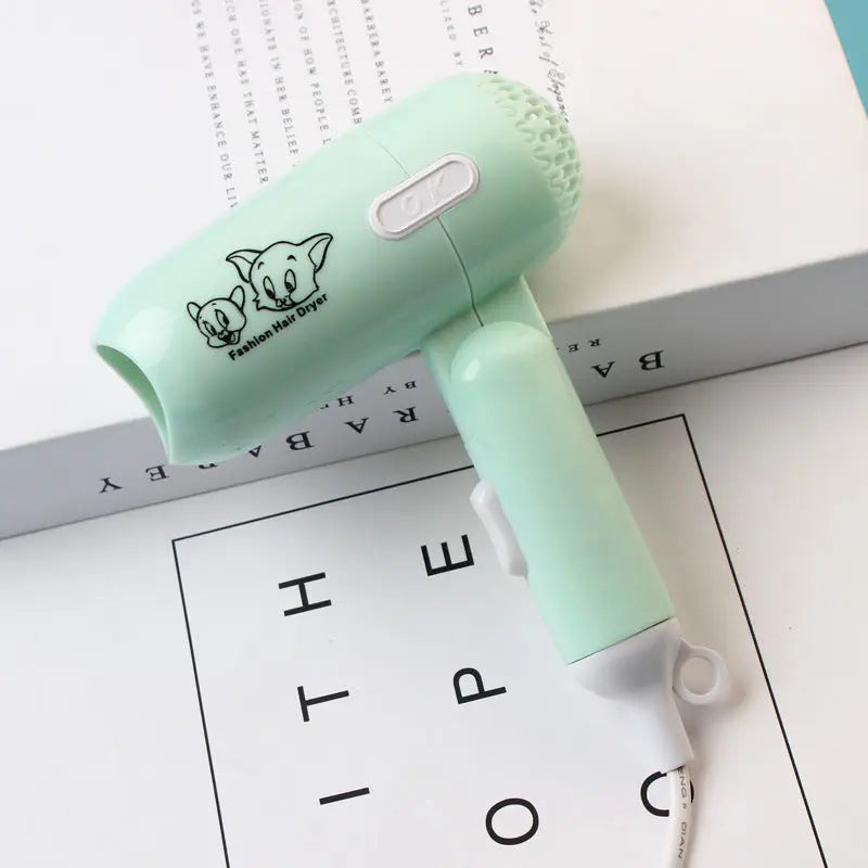 Small green hair dryer with cartoon character on a white surface with text