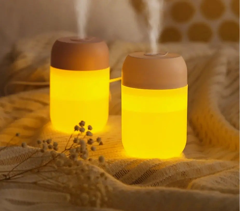 Two glowing diffusers emitting mist on a textured surface.